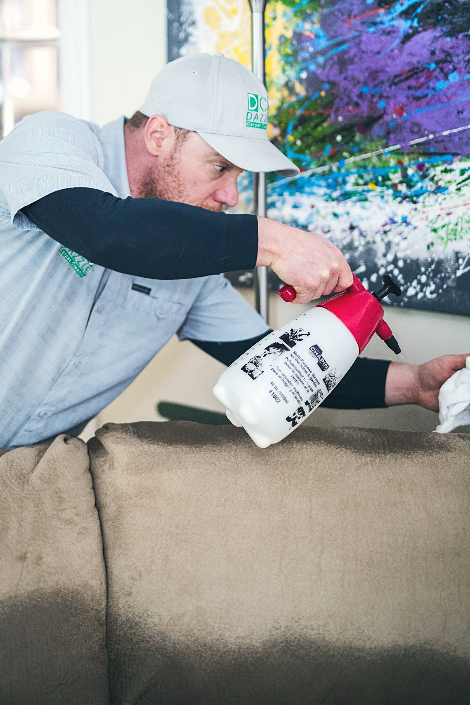 Technician spraying a fabric sofa with protector