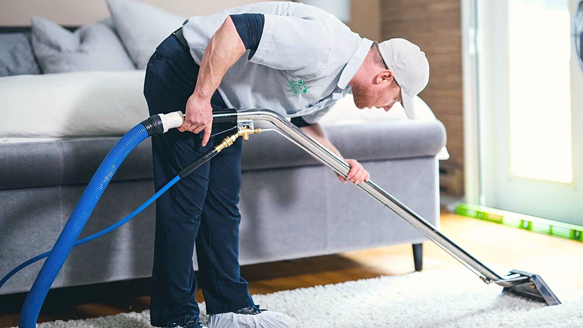 Technician cleaning a rug in front of a sofa in a Vancouver living room