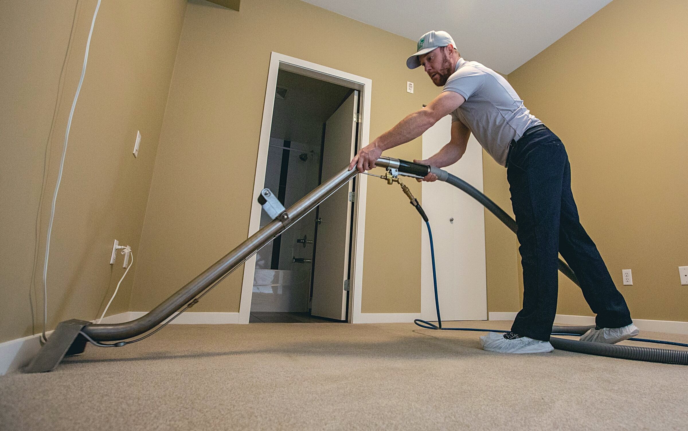 Technician cleaning the carpet in an empty room before a move-out